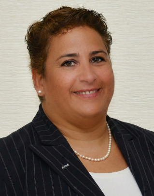 A diverse group of professionals engaging in a collaborative meeting around a laptop in an office.